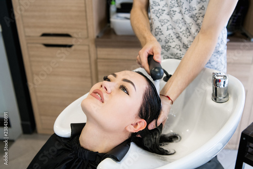 Female client getting hair washed by hairstylist in parlor