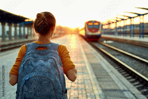 portrait of a young woman traveler with small backpack on the railway stantion