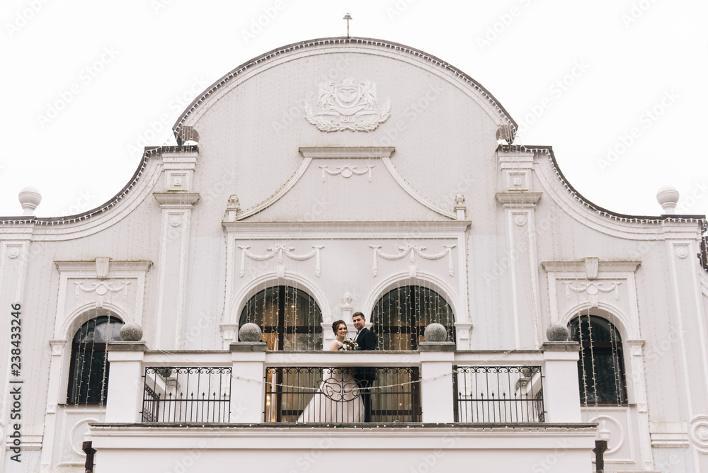 Portrait of happy young lovers of the bride and groom on the balcony of a beautiful hotel. Wedding day