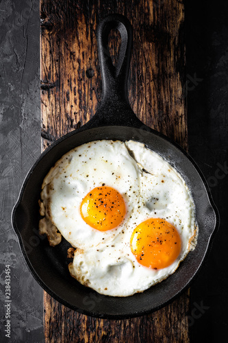 fried eggs in black skillet top view with space for a text