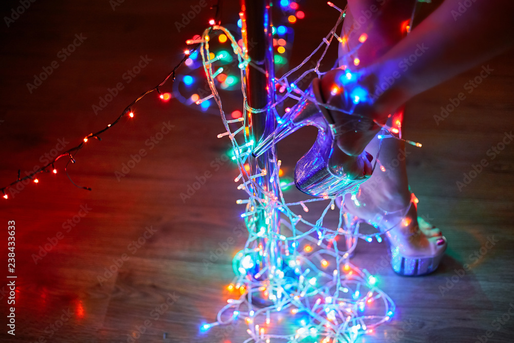 Female legs in Strip shoes dancing on a pole silver shoes wrapped by bunch of Christmas lights Stock Photo Adobe Stock