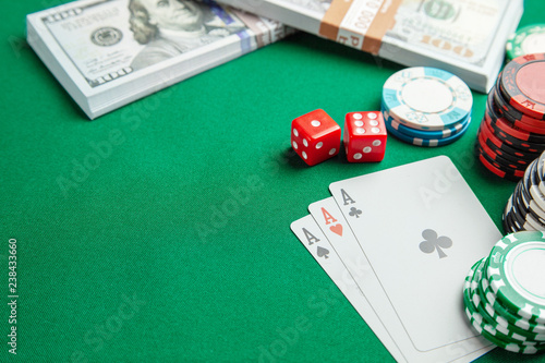 Concept of gambling in casino, sports poker. Playing cards with dice and colored chips with cash money dollars on green gaming table. Copy space for text