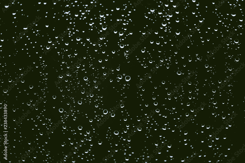 Dirty window glass with drops of rain. Atmospheric green background with raindrops. Droplets and stains close up. Detailed transparent texture in macro with copy space. Rainy weather. Dirty window glass with drops of rain. Atmospheric green background with raindrops. Droplets and stains close up. Detailed transparent texture in macro with copy space. Rainy weather.