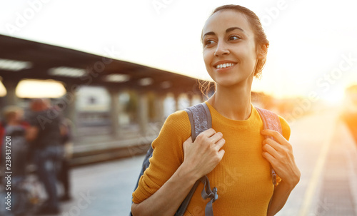 portrait of a young woman traveler with small backpack on the railway stantion