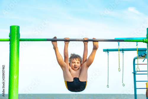 The boy on the uneven bars beats himself on the seashore, heavy exercise for the child.