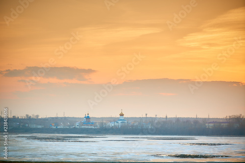 sunset over the Orthodox monastery. Russian city in the spring, ice on the river photo