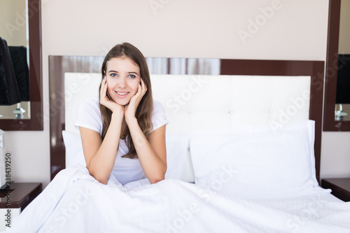 Young woman stretching in bed after wake up, back view