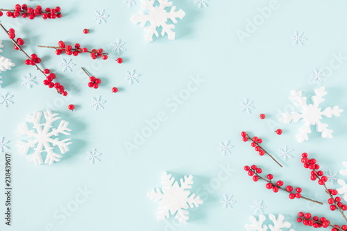 Christmas modern composition. Frame made of red berries and snowflakes on pastel blue background. Christmas, New Year, winter concept. Flat lay, top view, copy space