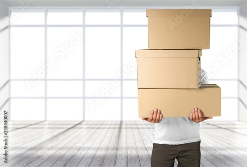 Delivery man carrying stacked boxes in front of face against