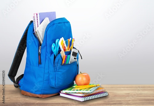 Colorful school supplies in backpack on wooden background