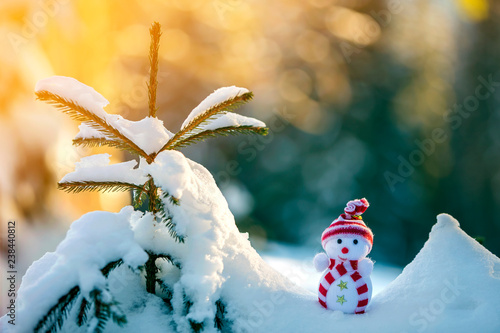 Photography Small funny toy baby snowman in knitted hat and scarf in deep snow outdoors on bright blue and white copy space background