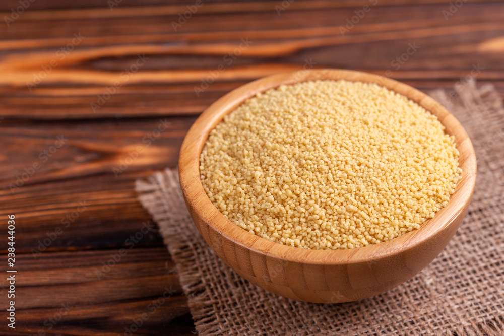 Raw couscous grain in wooden bowl with burlap napkin Raw couscous grain in wooden bowl with burlap napkin