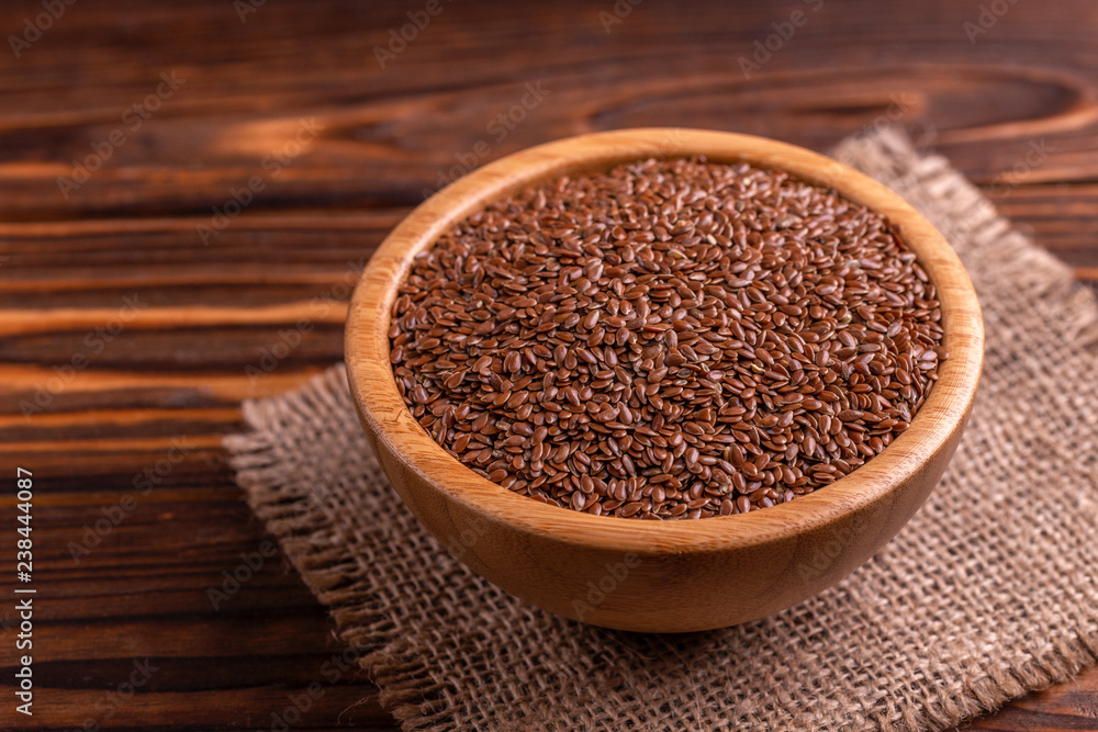 Raw flax seeds in wooden bowl with burlap napkin Raw flax seeds in wooden bowl with burlap napkin