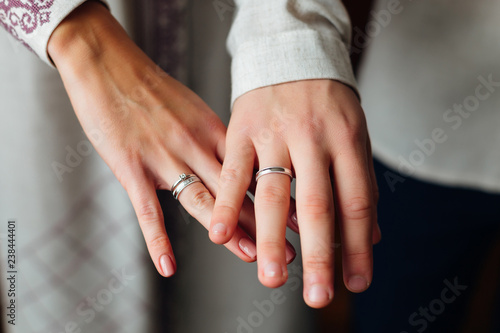 a close-up of hands of newlyweds on their fingers in which weddi