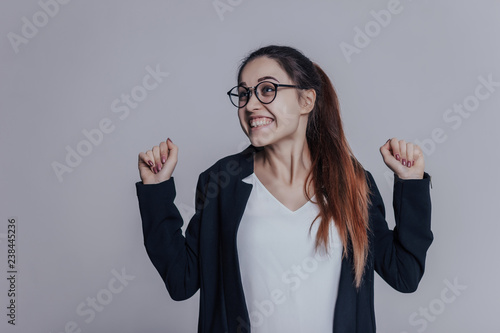 i'm so excited! The pretty girl in glasses very happy and cheerful. Woman clench your hands in fists for good luck.