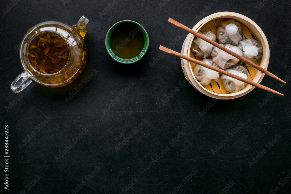 Chinese food set with dim sum, sticks and tea on black background top view copy space