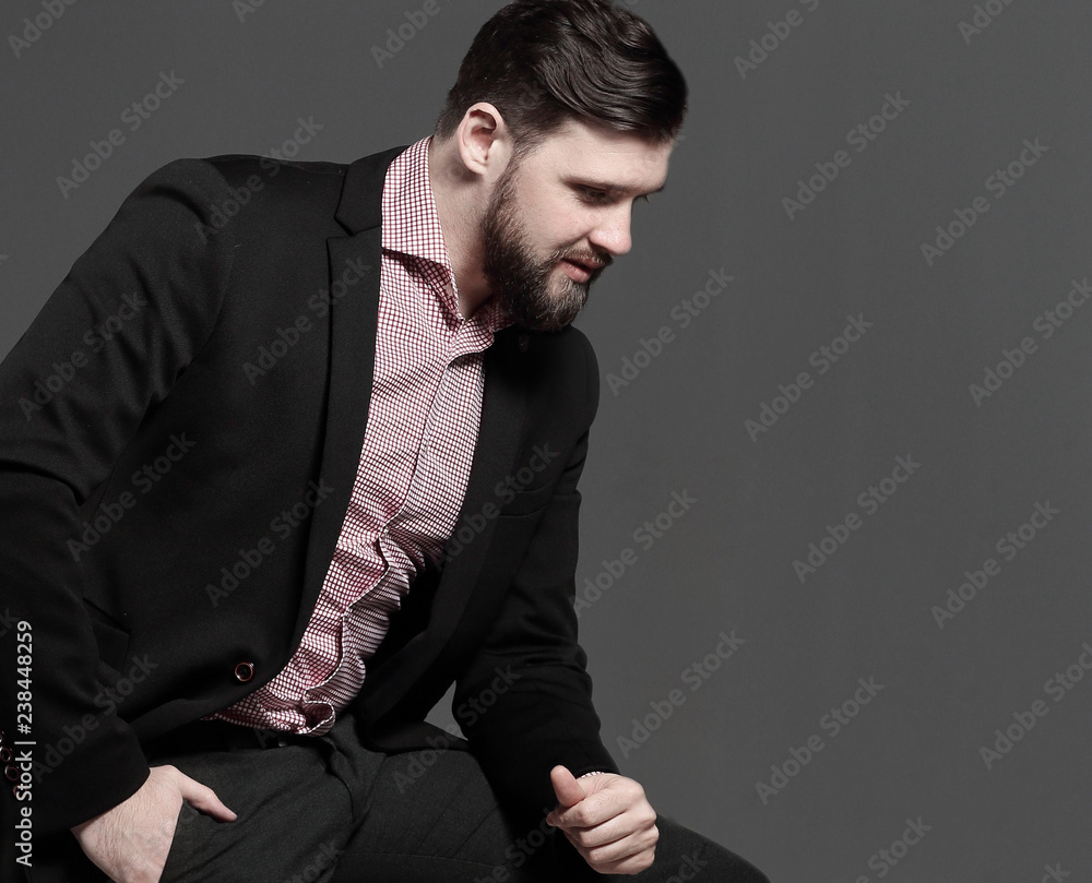 portrait of a stylish business man sitting on the back of a chair.isolated on grey background