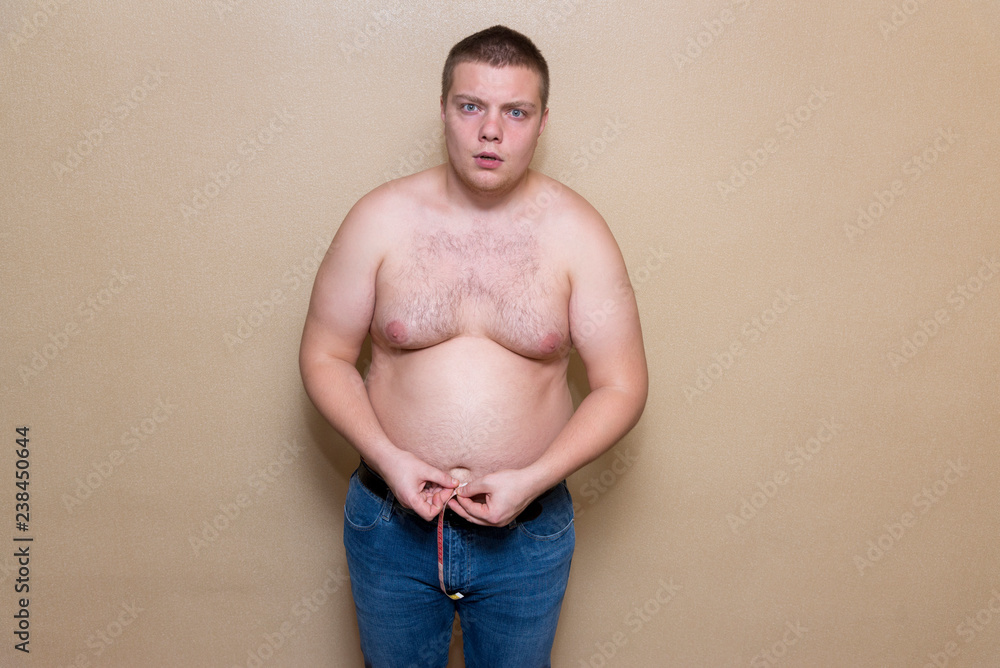 Naklejka premium A man measures his fat belly with a meter