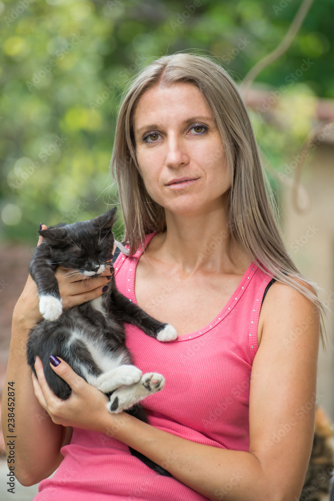 Girl holding a black cat with a blurred background