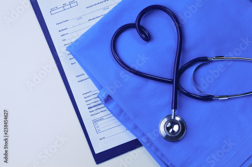 A stethoscope shaping a heart on a medical uniform, closeup, selective focus