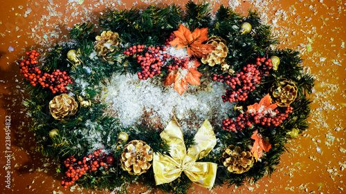 Snow falling on thhe Christmas Wreath on the brown background