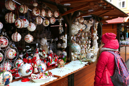 Little girl walking on Christmas market in Europe on holidays. Wooden multi-colored Christmas toys for decorating house at Xmas Market 