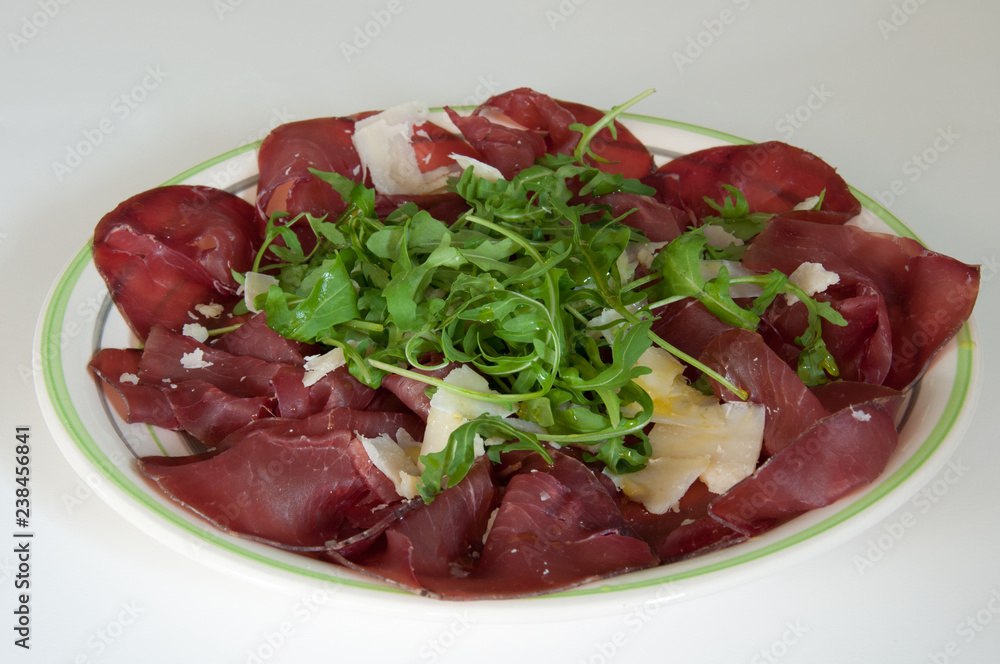 Piatto di bresaola con rucola e parmigiano in primo piano. Tipico cibo italiano. Piatto di bresaola con rucola e parmigiano in primo piano. Tipico cibo italiano.