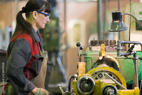 Metalwork industry. Factory woman turner working at workshop lathe machine