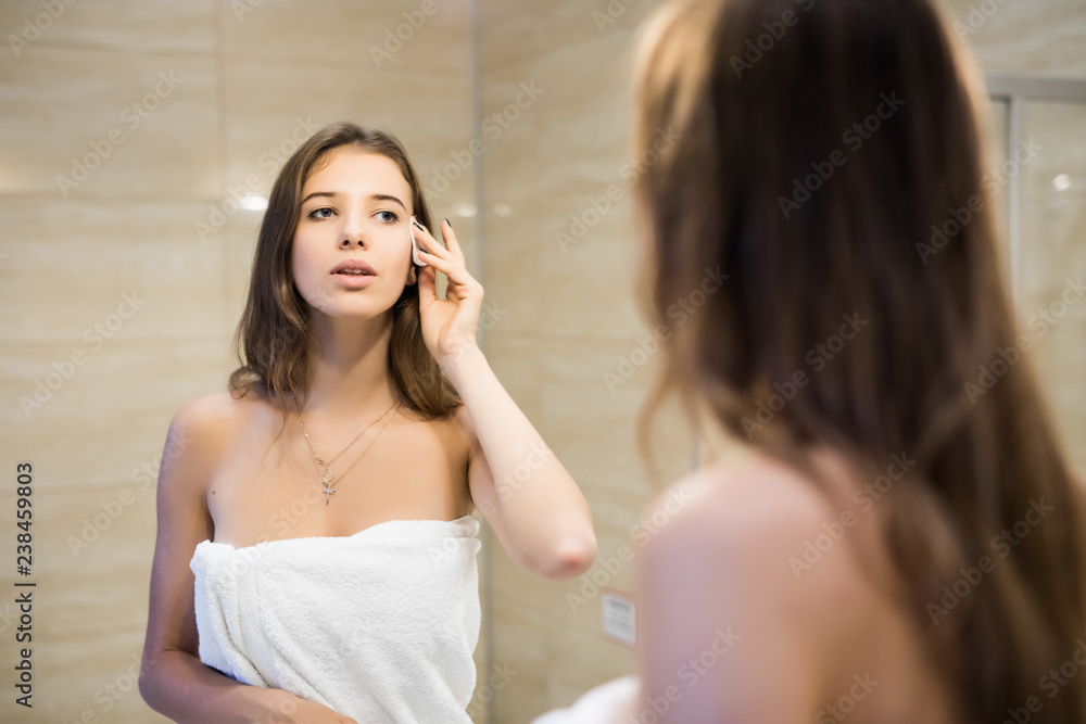 Happy attractive woman after shower removing makeup in the bathroom