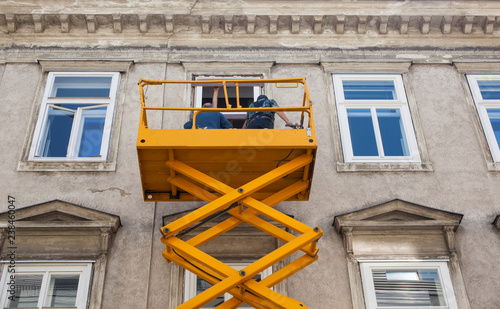 Workers on a cherry picker refurbish the facade of a building photo