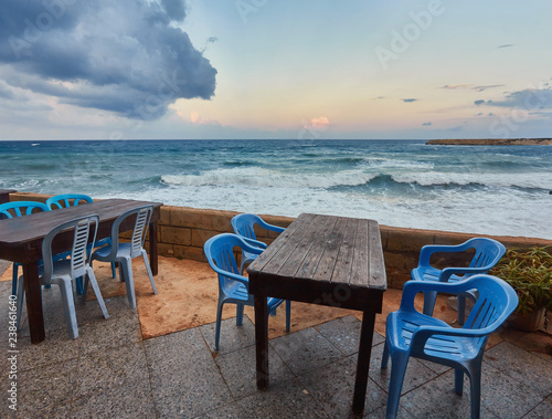 Tables and chairs in a cafe with palm trees on the beach Lara