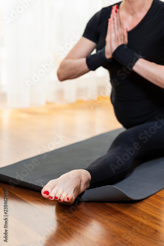 Closeup of Legs of Caucasian Woman Practicing Yoga Exercise Indoors At Bright Afternoon. Sitting in Hanu Manasana Pose During Solitude Meditation Session.