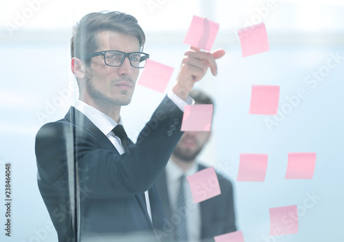 serious employee reads a sticker-note on the office Board. photo