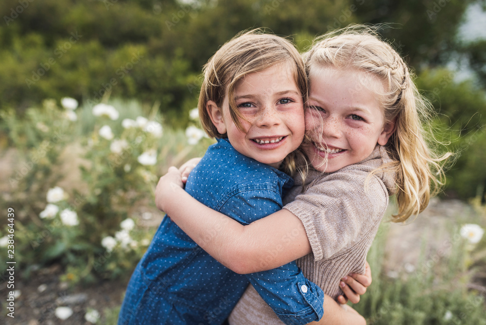 Portrait of smiling sisters embracing in forest Portrait of smiling sisters embracing in forest