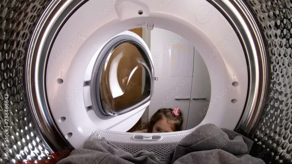 Little girl loading her stuffed toy to washing machine. View from the inside of washing machine. Little girl loading her stuffed toy to washing machine. View from the inside of washing machine.