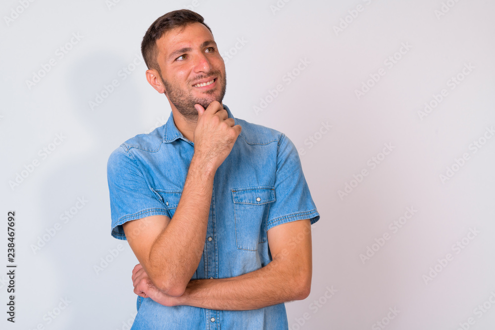 Happy bearded Persian man thinking while looking up against white background Happy bearded Persian man thinking while looking up against white background