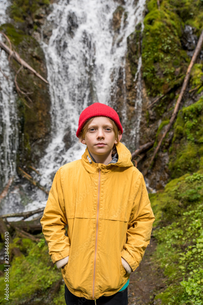 Portrait of boy with hands in pockets standing against waterfall in Olympic National Park Portrait of boy with hands in pockets standing against waterfall in Olympic National Park