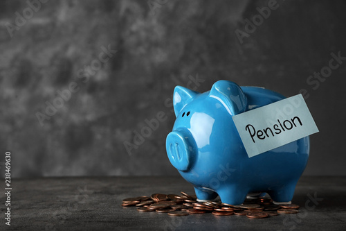 Piggy bank with word PENSION and coins on table. Space for text
