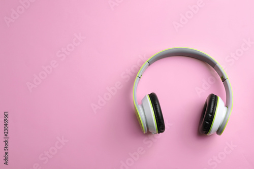 Wireless headphones on color background, top view. Space for text