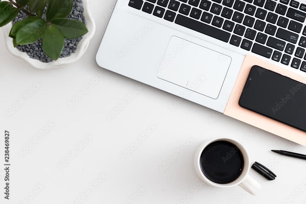 White office desk with laptop office plant and notebook and mobile phone White office desk with laptop office plant and notebook and mobile phone