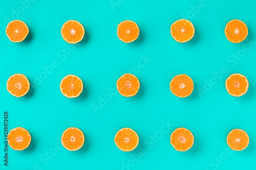 Fototapeta Naklejka Na Ścianę i Meble -  Fruit pattern of fresh mandarin slices on blue background. Flat lay, top view. Pop art design, creative summer concept. Half of citrus in minimal style. Tangerine.