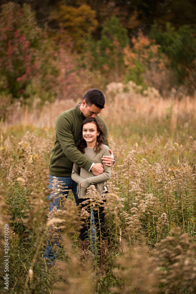 Father kissing on daughter's head while standing amidst plants in forest Father kissing on daughter's head while standing amidst plants in forest