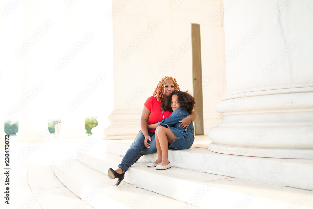 Portrait of daughter embracing mother while sitting on steps against columns Portrait of daughter embracing mother while sitting on steps against columns