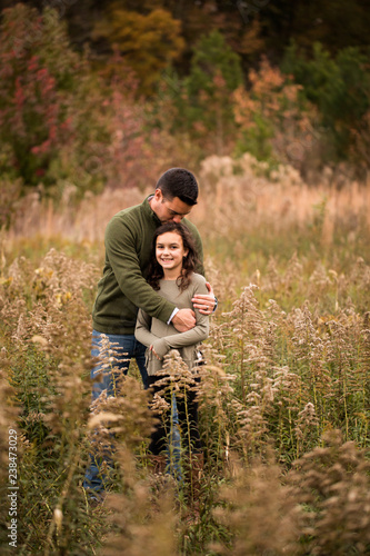 Father kissing on daughter's head while standing amidst plants in forest photo