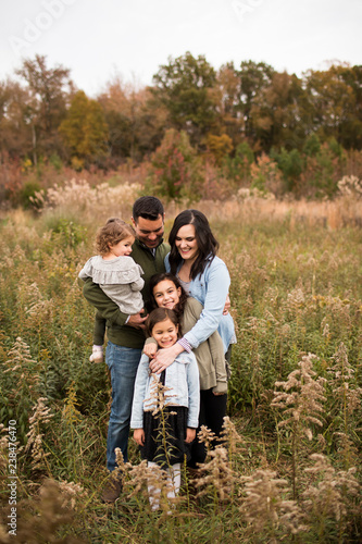 Smiling parents with daughters standing amidst plants against sky in forest photo