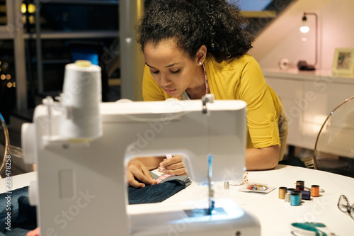 Female entrepreneur measuring jeans on table in office photo