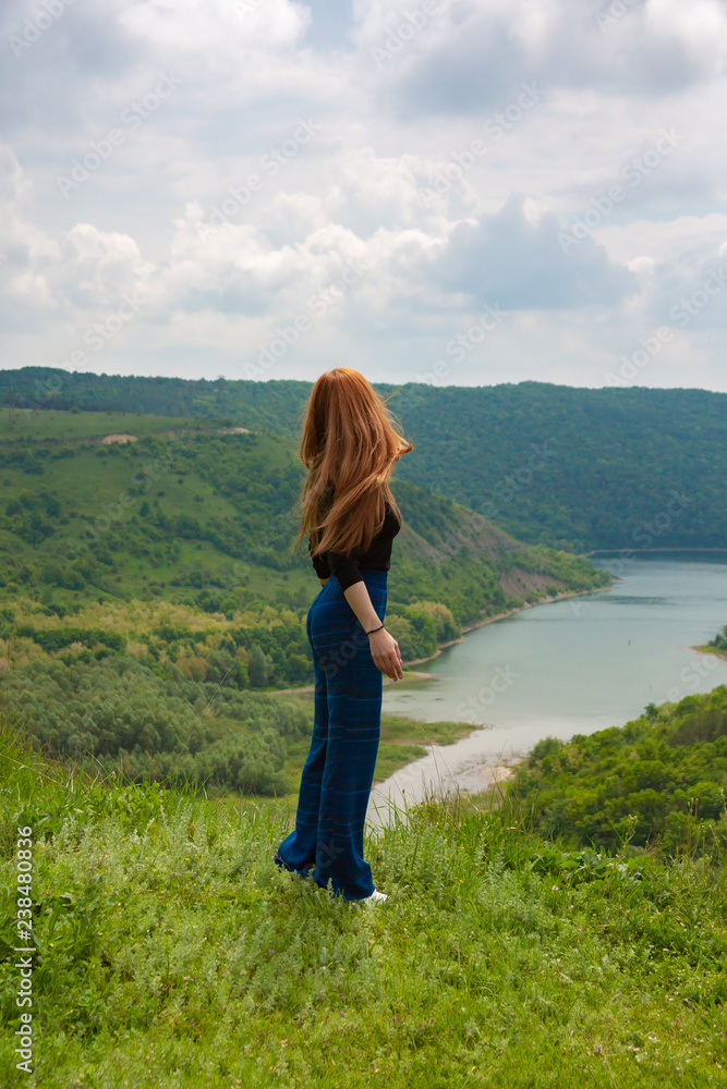 A beautiful girl tourist enjoys nature next to a mountain river