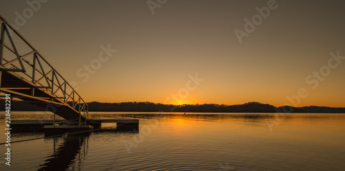 Beautiful yellow orange sunrise sunset over Dale Hollow Lake with a bridge to a fishing pier. Concepts of vacation, travel, tourism