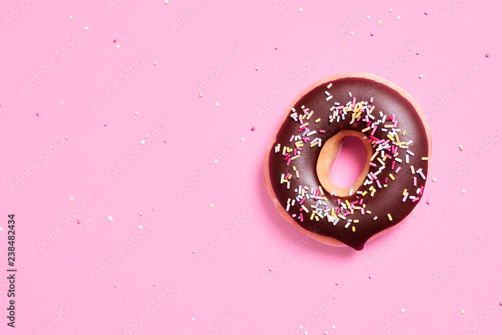 Overhead view of chocolate donut with sprinkles on pink background Overhead view of chocolate donut with sprinkles on pink background