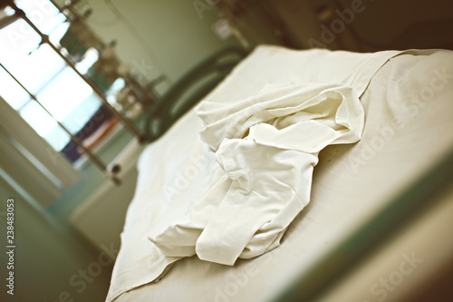 Empty abandoned bed with rumpled bed-clothes in a hospital ward